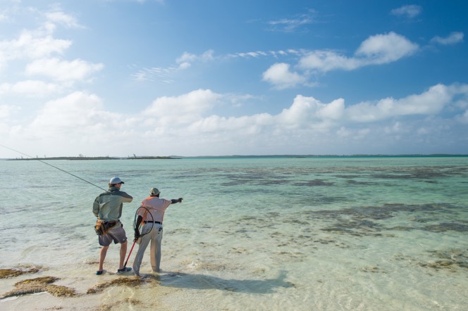 A guide points out a fish to an angler in the Bahamas.